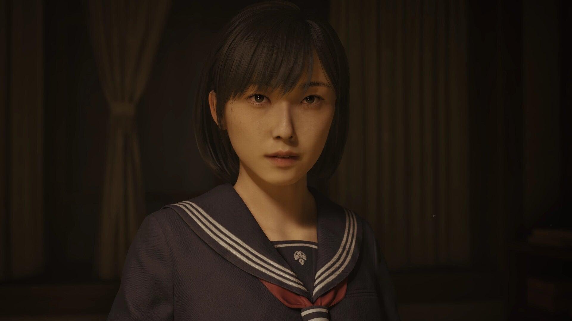 The Japanese schoolgirl heroine of Silent Hill f, standing in a shadowy environment looking toward the camera